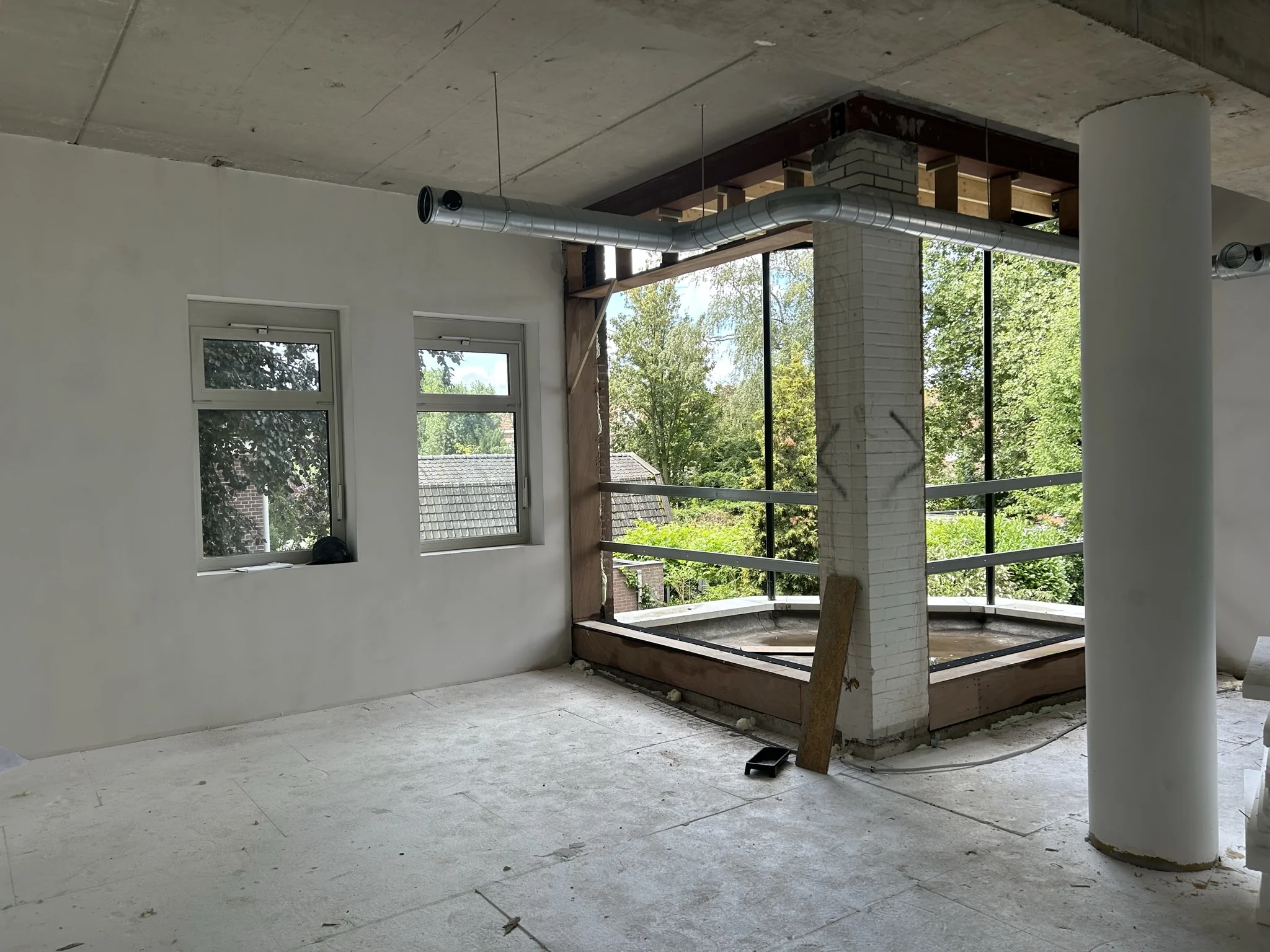 Interieur van een pand aan de Bergse Dorpsstraat in verbouwing met grote ramen en zicht op groen.